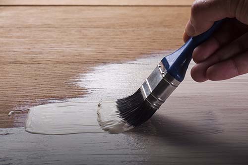 applying varnish paint on a wooden surface